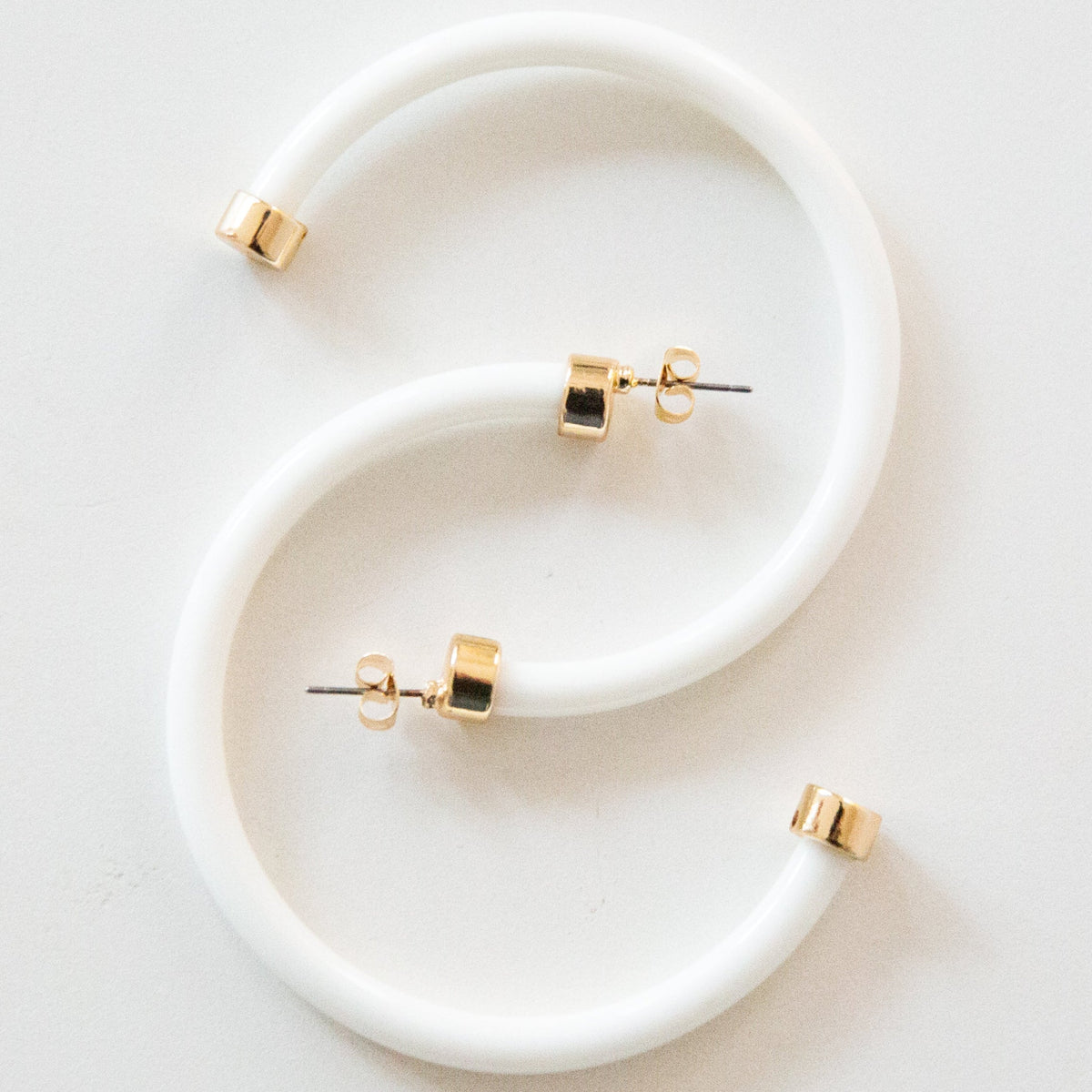 White hoop earrings by hoohoops featuring large, smooth circular design on a white background.