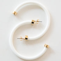 White hoop earrings by hoohoops featuring large, smooth circular design on a white background.