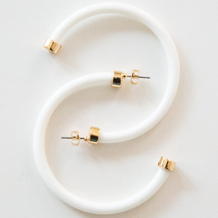 White hoop earrings by hoohoops featuring large, smooth circular design on a white background.