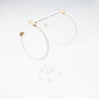 White hoop earrings by hoohoops, showing close-up of sleek circular jewelry on a model's ear.