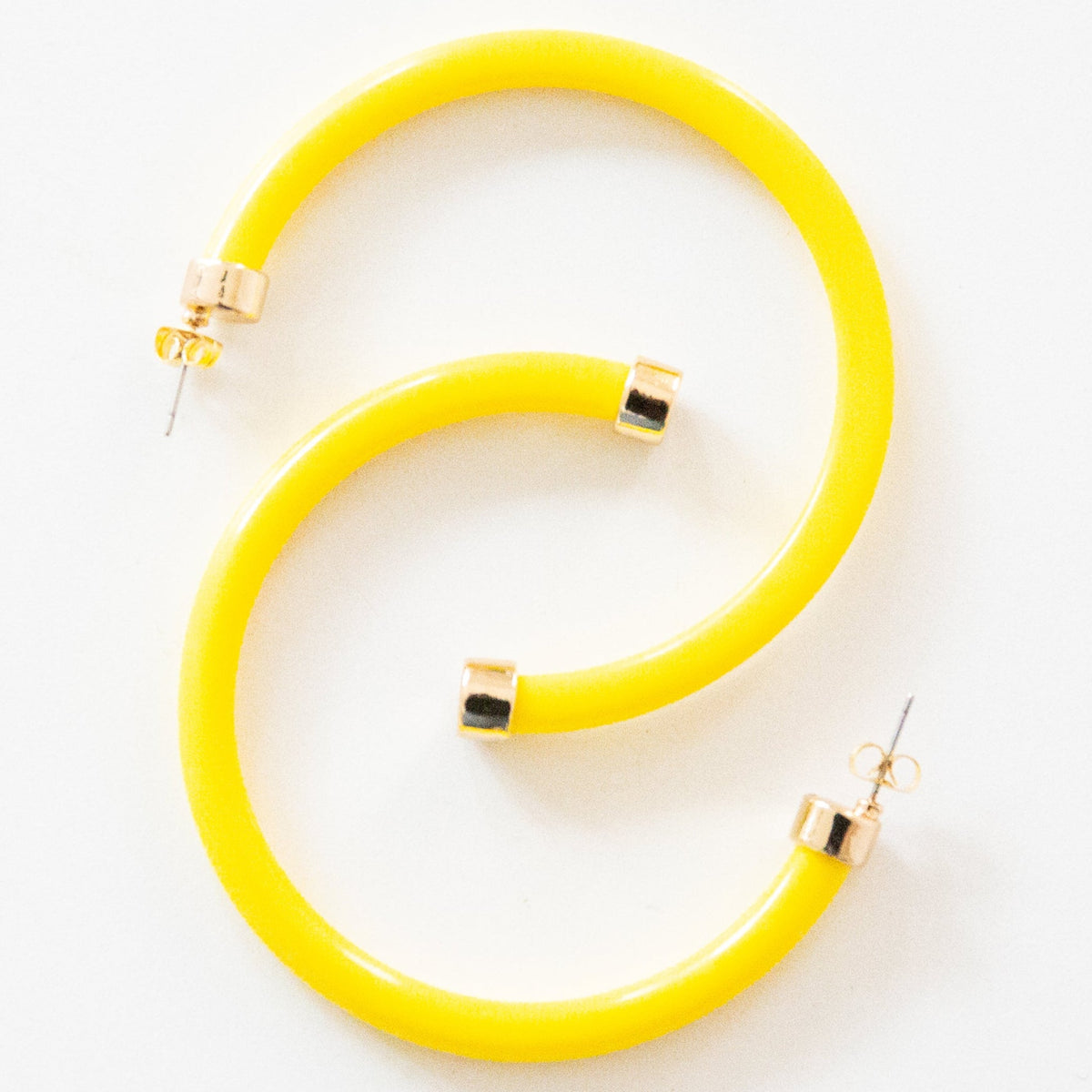 Yellow hoop earrings by hoohoops, showing stylish gold-tone hoops with a smooth finish on a neutral background.