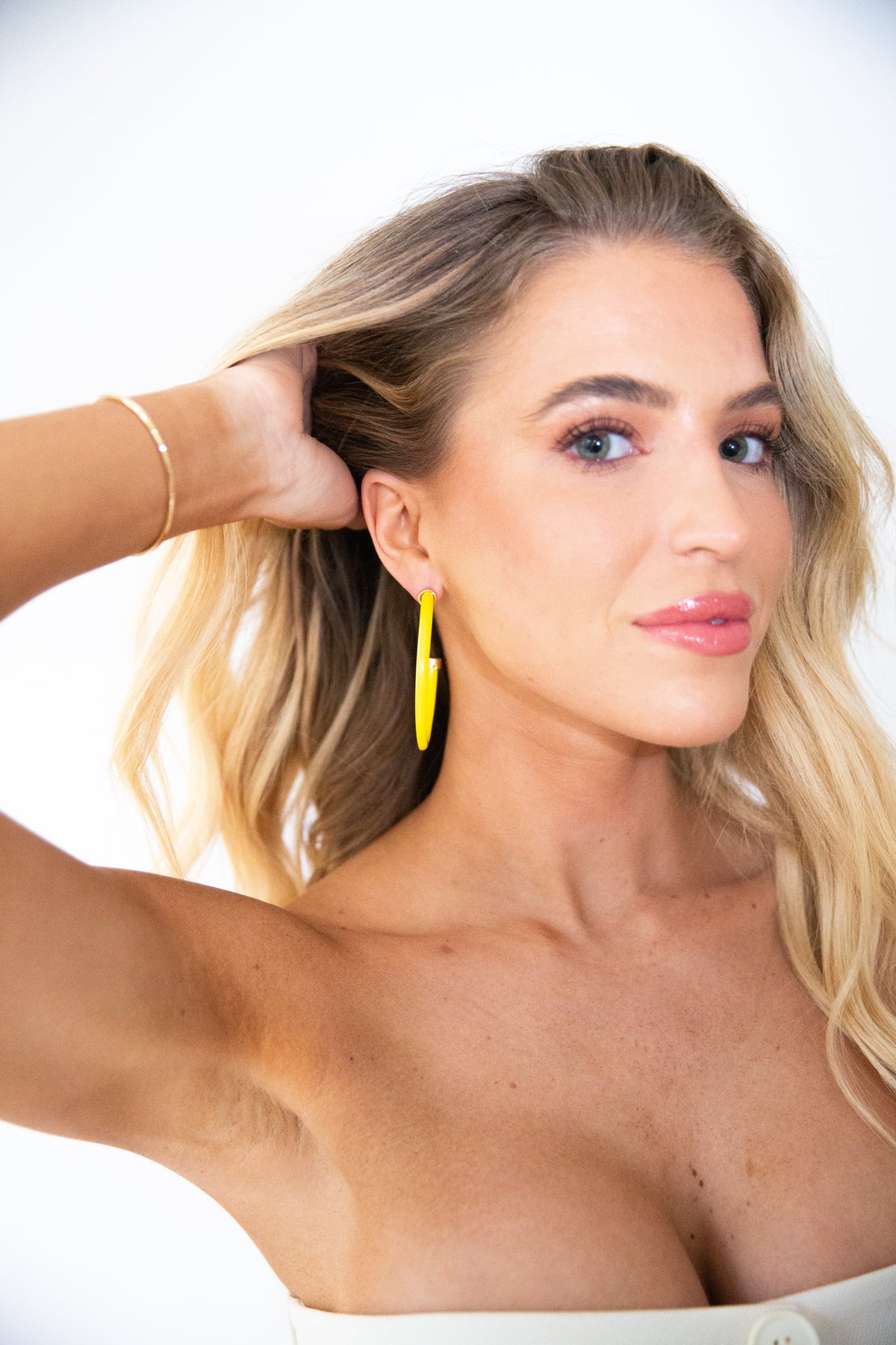 Yellow hoop earrings by hoohoops featuring large, circular gold-toned hoops on a white background.