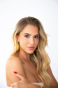 Yellow hoop earrings by hoohoops featuring large, circular gold-toned hoops hanging from a simple hook design.