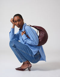 HYER GOODS burgundy leather ring-shaped hobo bag with adjustable strap and minimalist design.