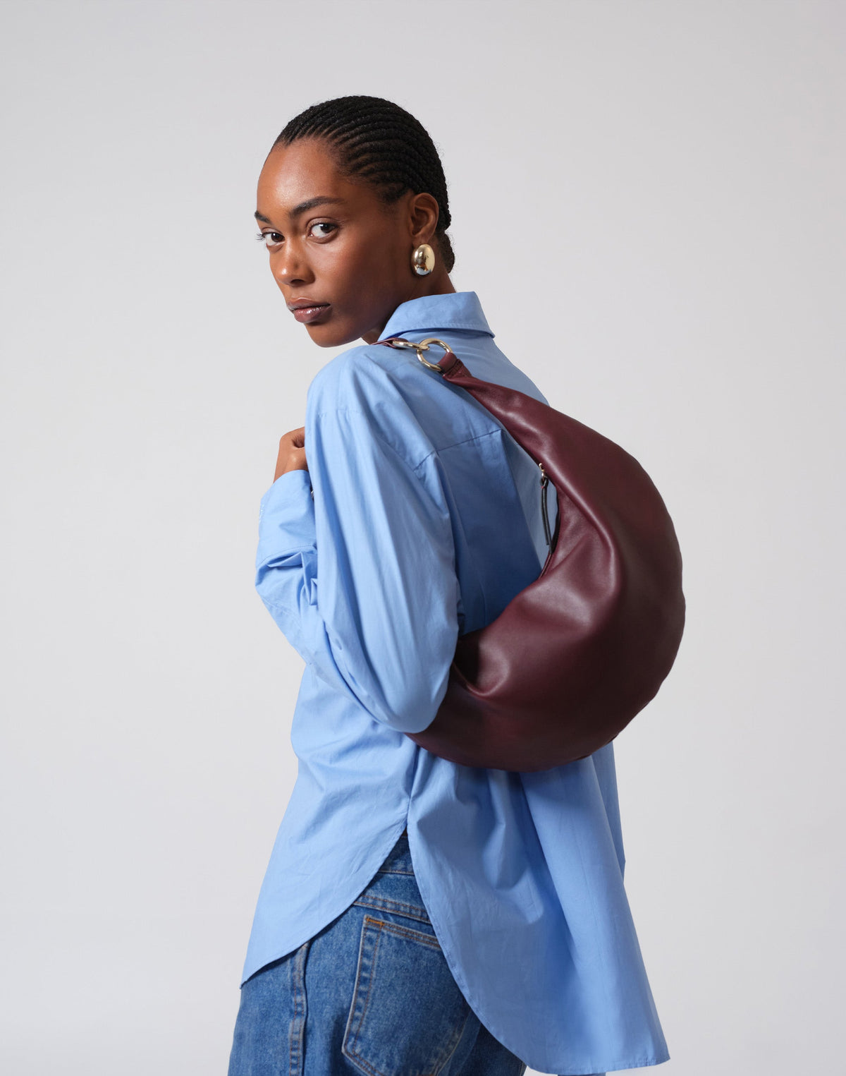 Burgundy The Ring Hobo Bag by HYER GOODS shown on shoulder, featuring a sleek, modern design and smooth leather finish.