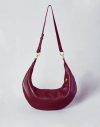 HYER GOODS Ring Bag in Bordeaux with long strap, hobo style, featuring a rounded ring design and soft leather texture.