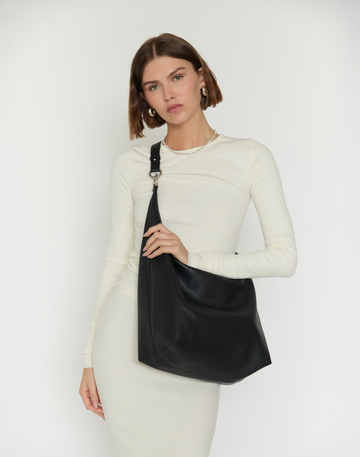 Black and silver HYER GOODS Hobo Ring Bag with adjustable strap, styled as an elegant x-body bag.