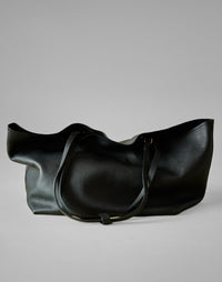 Black HYER GOODS Mercato tote bag with soft texture, shown on a grey background, highlighting its spacious design.