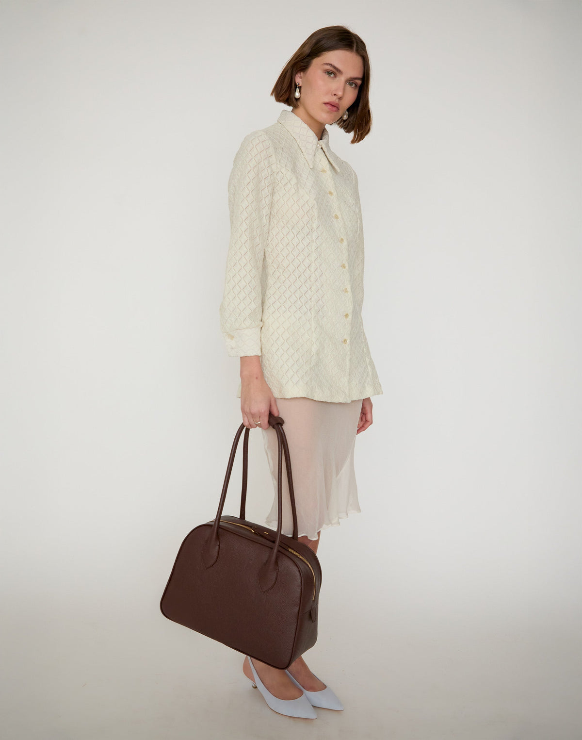 HYER GOODS La Autostrada Tote Bag in brown, held by hand, showcasing its spacious design and sturdy handles.