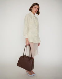 HYER GOODS La Autostrada Tote Bag in brown, held by hand, showcasing its spacious design and sturdy handles.