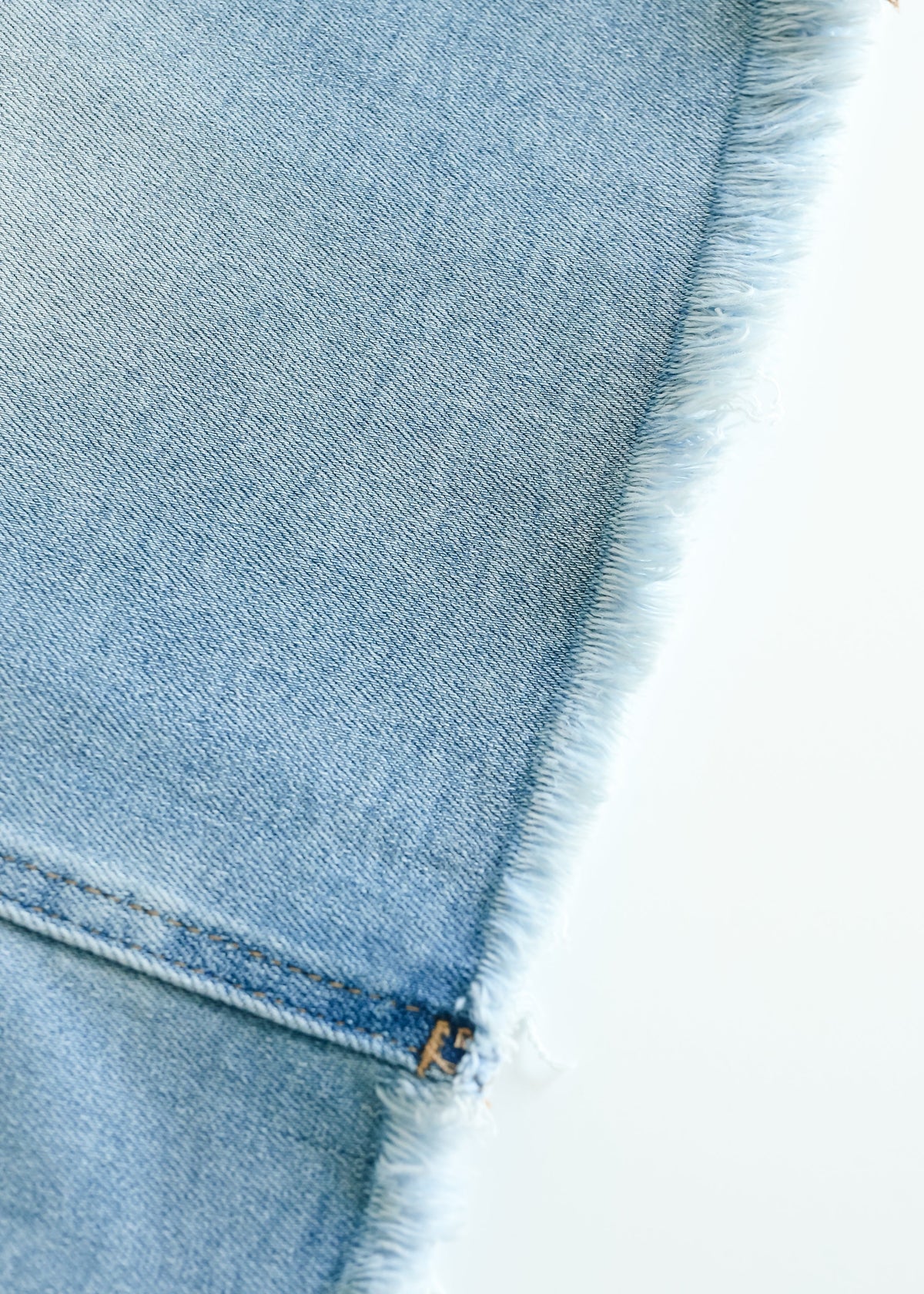 Inherit Co. Drew Raw Hem Midi Denim Skirt with side pockets, showcasing classic blue denim and a raw hem detail.