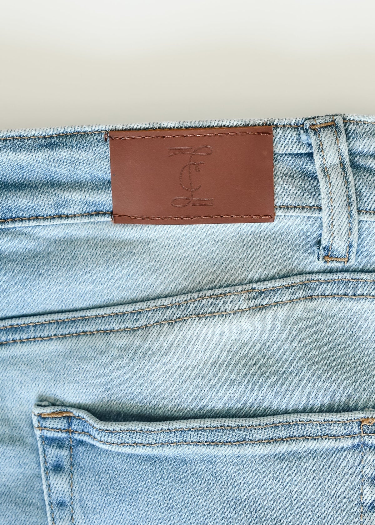 Inherit Co. Drew Raw Hem Midi Denim Skirt with button-front, high waist, and classic blue wash, displayed on a hanger.