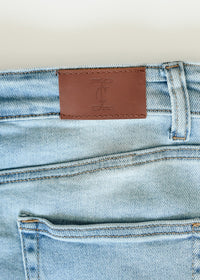Inherit Co. Drew Raw Hem Midi Denim Skirt with button-front, high waist, and classic blue wash, displayed on a hanger.