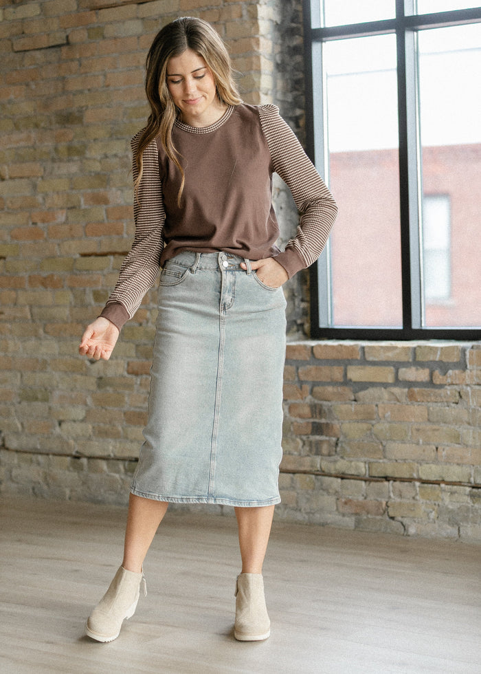 Light wash midi denim skirt from Inherit Co., featuring a classic A-line silhouette and casual style.