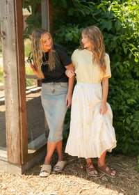 Light wash midi denim skirt from Inherit Co. featuring classic five-pocket style and a flattering A-line silhouette.