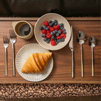 Italic Emilia Mirror 20-piece flatware set with gold finish, includes forks, knives, spoons, and serving utensils arranged on a white background.