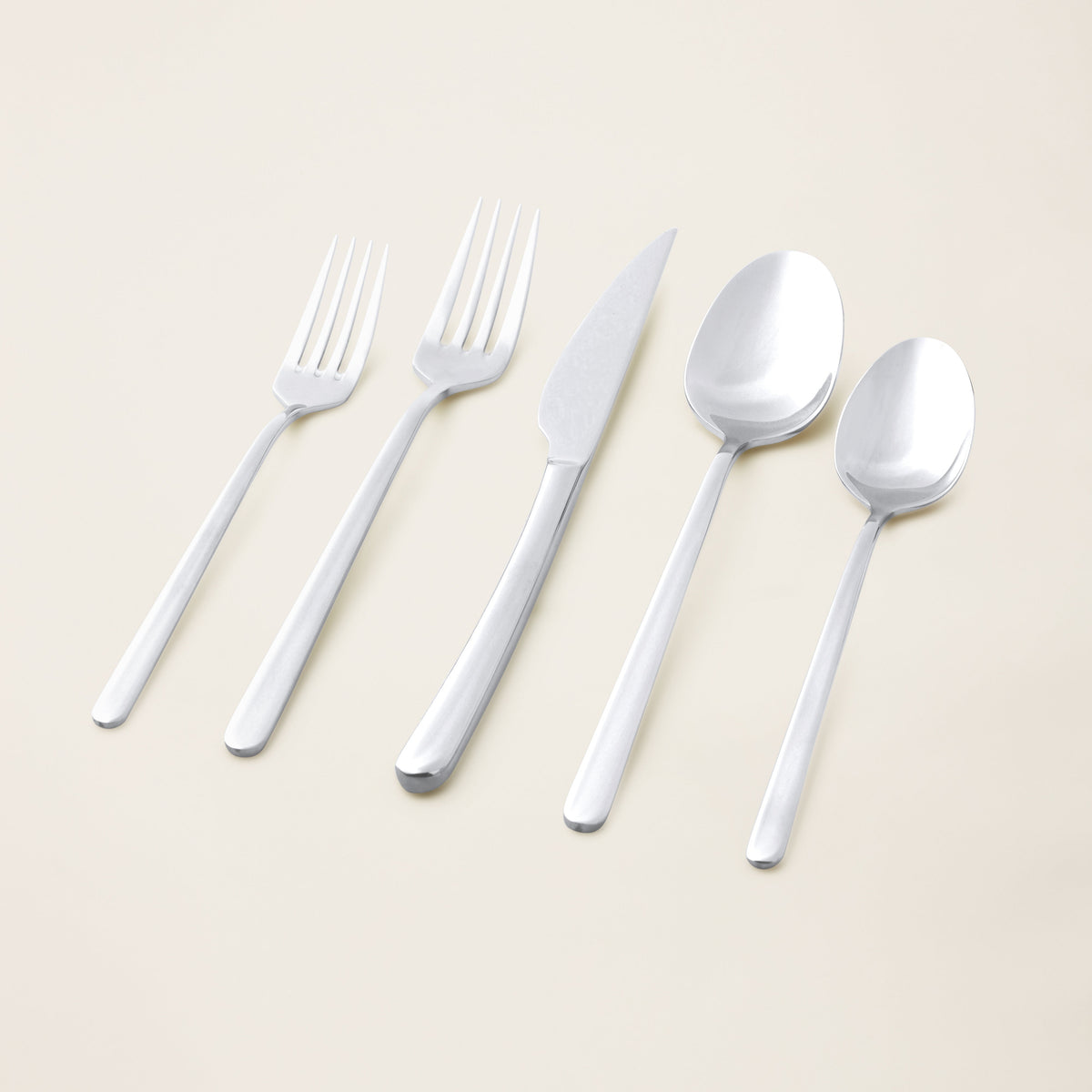 Italic Emilia 20-piece mirror finish flatware set with sleek gold stainless steel utensils arranged on a white background.