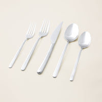 Italic Emilia 20-piece mirror finish flatware set with sleek gold stainless steel utensils arranged on a white background.