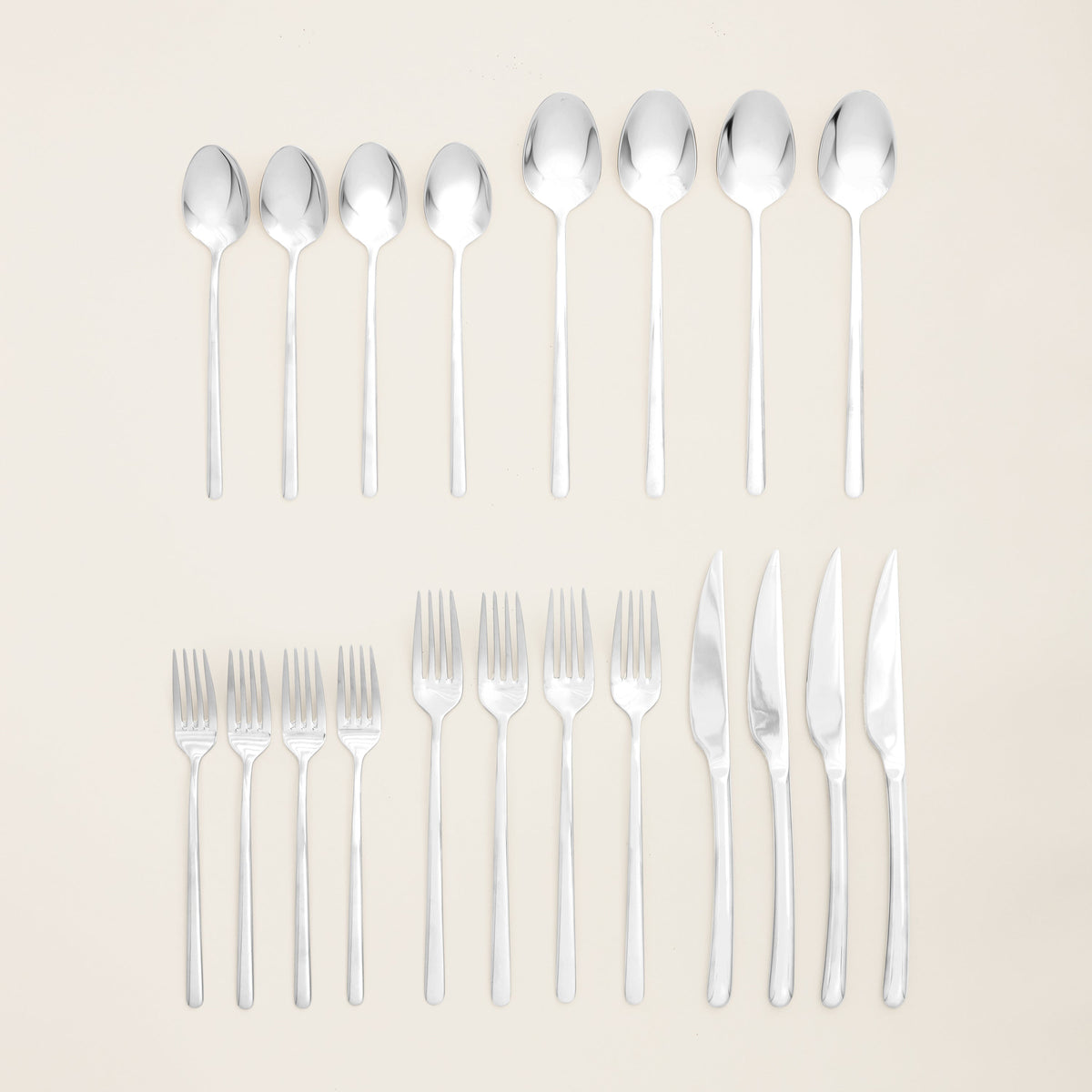 Italic Emilia Mirror 20-piece flatware set featuring gold stainless steel forks, knives, spoons, and teaspoons arranged neatly.