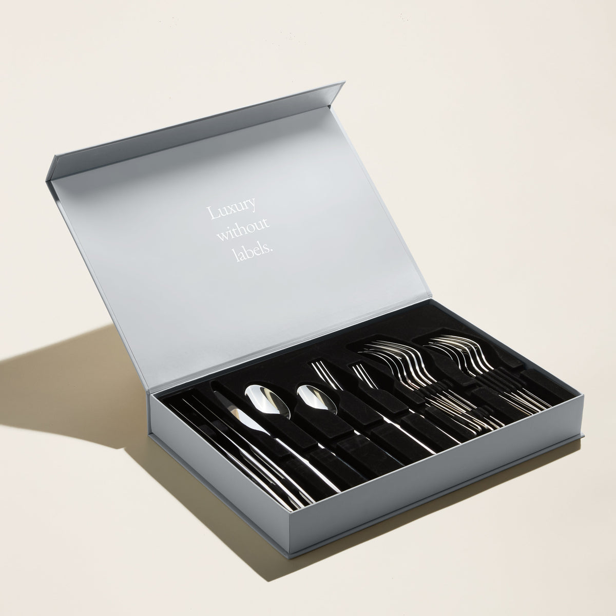 Italic Emilia 20-piece flatware set with gold mirror finish, including forks, knives, spoons, and teaspoons arranged on a white background.