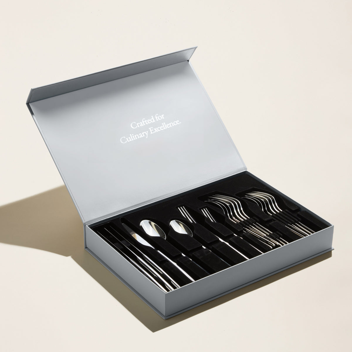 Italic Emilia 20-piece flatware set with gold mirror finish, including forks, knives, spoons, and teaspoons arranged on a white background.