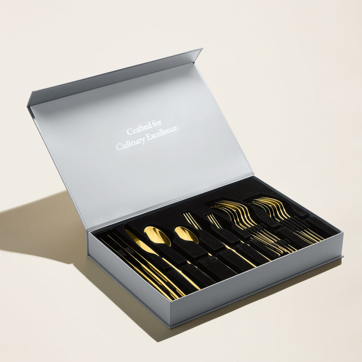 Italic Emilia Mirror 20-piece flatware set featuring gold finish and sleek design, including forks, knives, spoons, and serving utensils.