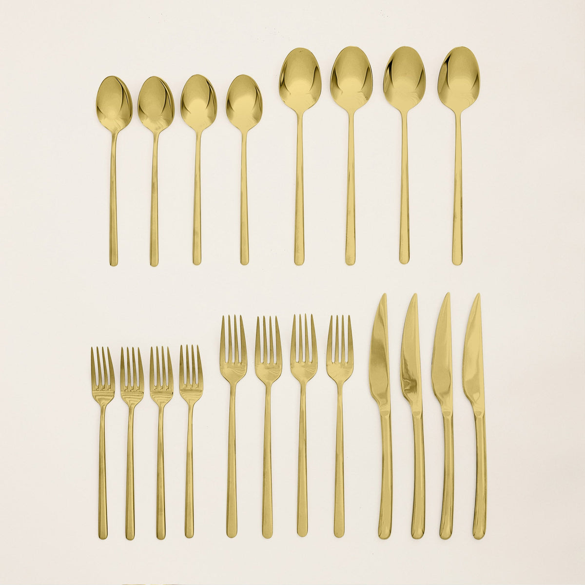 Italic Emilia Mirror 20-piece flatware set with gold finish, featuring forks, knives, spoons, and teaspoons arranged on a white background.