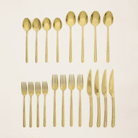 Italic Emilia Mirror 20-piece flatware set with gold finish, featuring forks, knives, spoons, and teaspoons arranged on a white background.