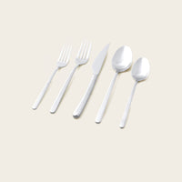 Italic Emilia Mirror 20-piece gold flatware set with sleek handles and polished finish, including forks, knives, spoons, and teaspoons.