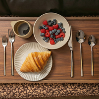 Italic Emilia Mirror 20-piece flatware set with gold finish, including forks, knives, spoons, and serving utensils.