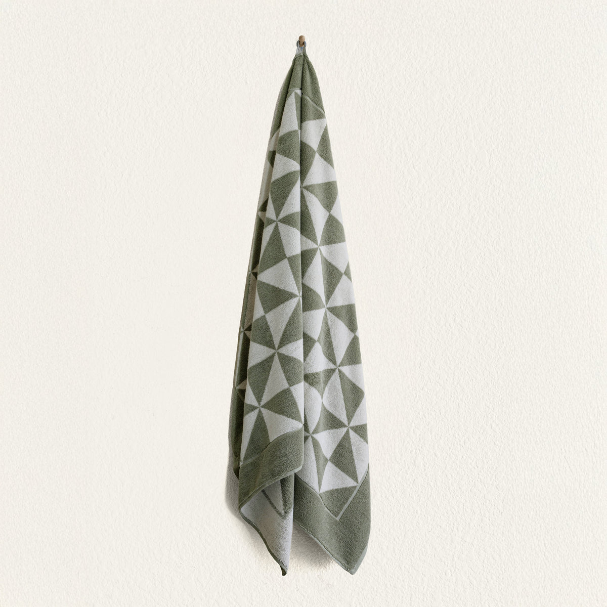 Set of two Italic Umbra bath towels in sage and ecru, soft and plush for home use, shown folded with textured fabric.