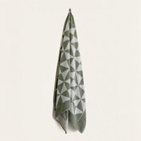Set of two Italic Umbra bath towels in sage and ecru, soft and plush for home use, shown folded with textured fabric.