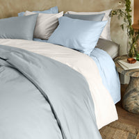 Blue and white Luxe Australian Sateen bedding bundle by Italic on a bed, showcasing smooth, luxurious satin fabric in a cozy home setting.