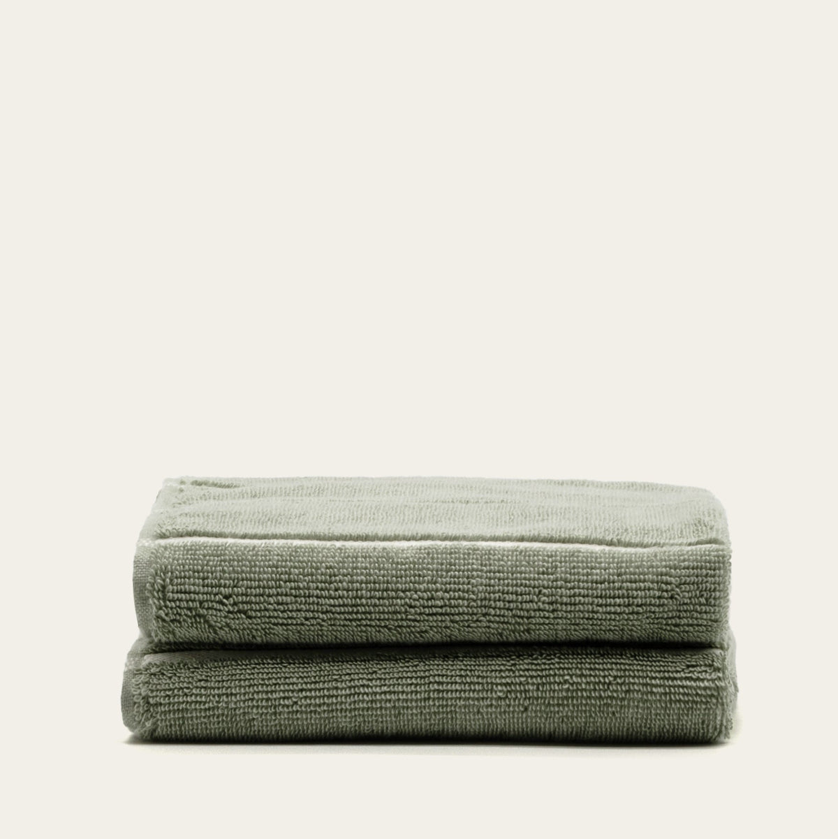 Set of two Italic Deia bed towels in sage and ecru, soft and plush home textiles for a cozy bedroom setting.