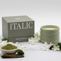 Italic Matcha Bloom ceramic candle in a decorative ceramic holder with a burning wick and floral design.