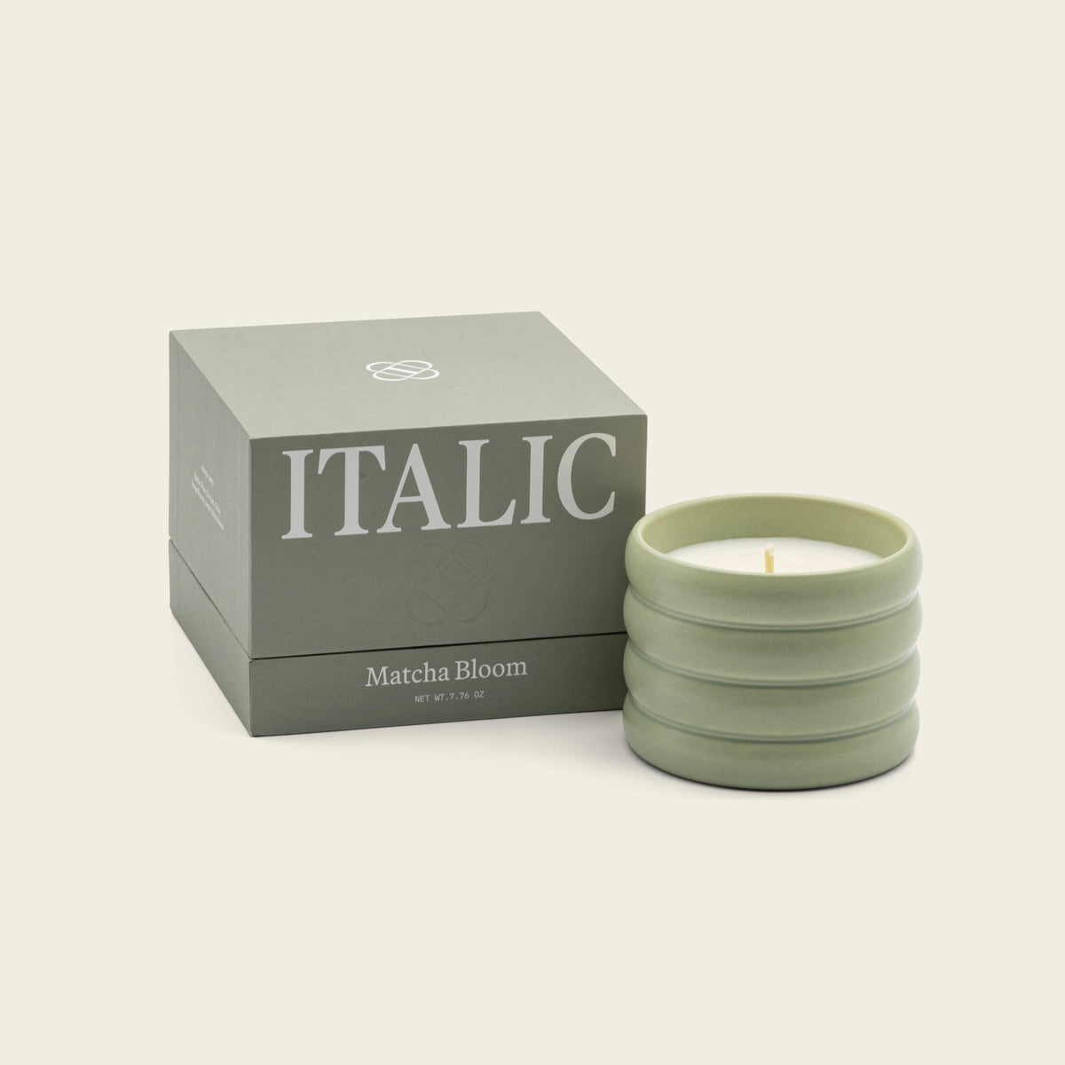 Italic Matcha Bloom ceramic candle in a decorative white ceramic holder with a lit wick and floral design.