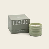 Italic Matcha Bloom ceramic candle in a decorative white ceramic holder with a lit wick and floral design.