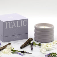 Italic Matcha Bloom ceramic candle in a white ceramic holder with a floral design and a lit wick, showcasing a cozy ambiance.