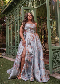 Blue Arabella Dress by JessaKae featuring a flowing fabric and elegant design, displayed on a hanger against a plain background.