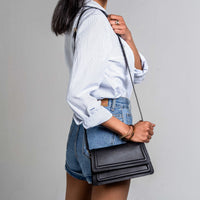 Black leather mini crossbody handbag with long strap from Kila Siku, featuring sleek design and compact size.