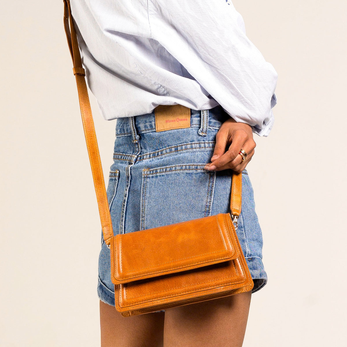 Camel leather mini crossbody bag from Kila Siku with a long strap, showcasing a sleek handbag design and textured leather finish.