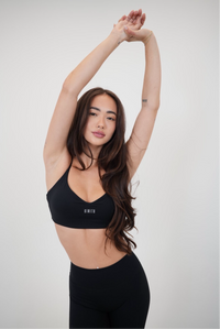 Black KIMITH BRAND sports bra with "I Live in Luxury" text, shown on a neutral background, designed for activewear comfort.