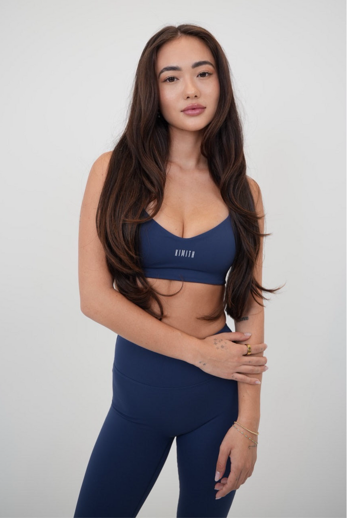 Navy blue sports bra by KIMITH BRAND with supportive design, shown on a white background.