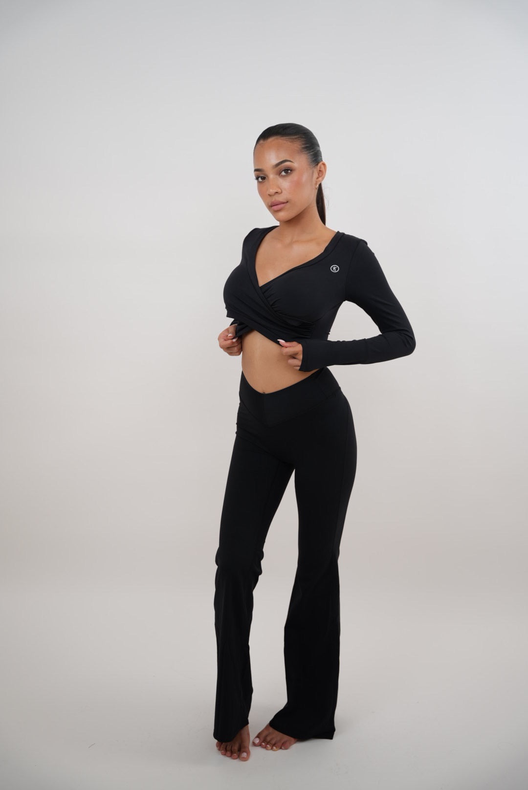 Black stretch flare legging by KIMITH BRAND featuring a fitted waistband and flared leg design, shown on a model.