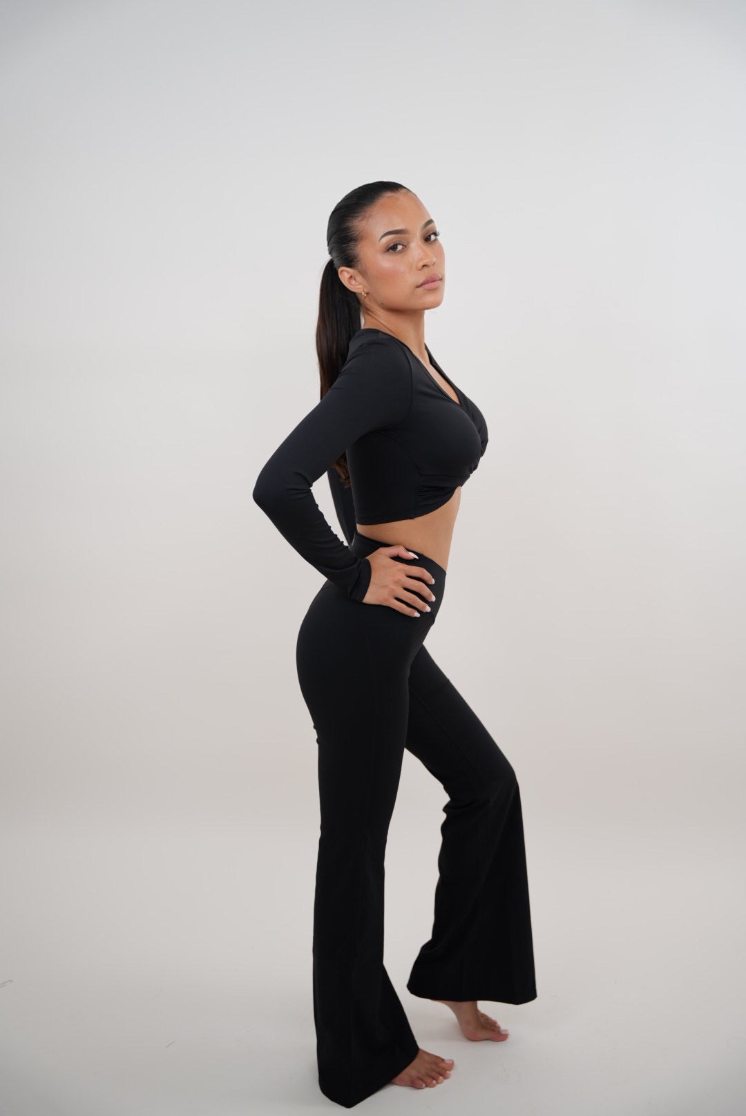 Black stretch flare leggings by KIMITH BRAND featuring a fitted waist and flared leg design, shown on a model.