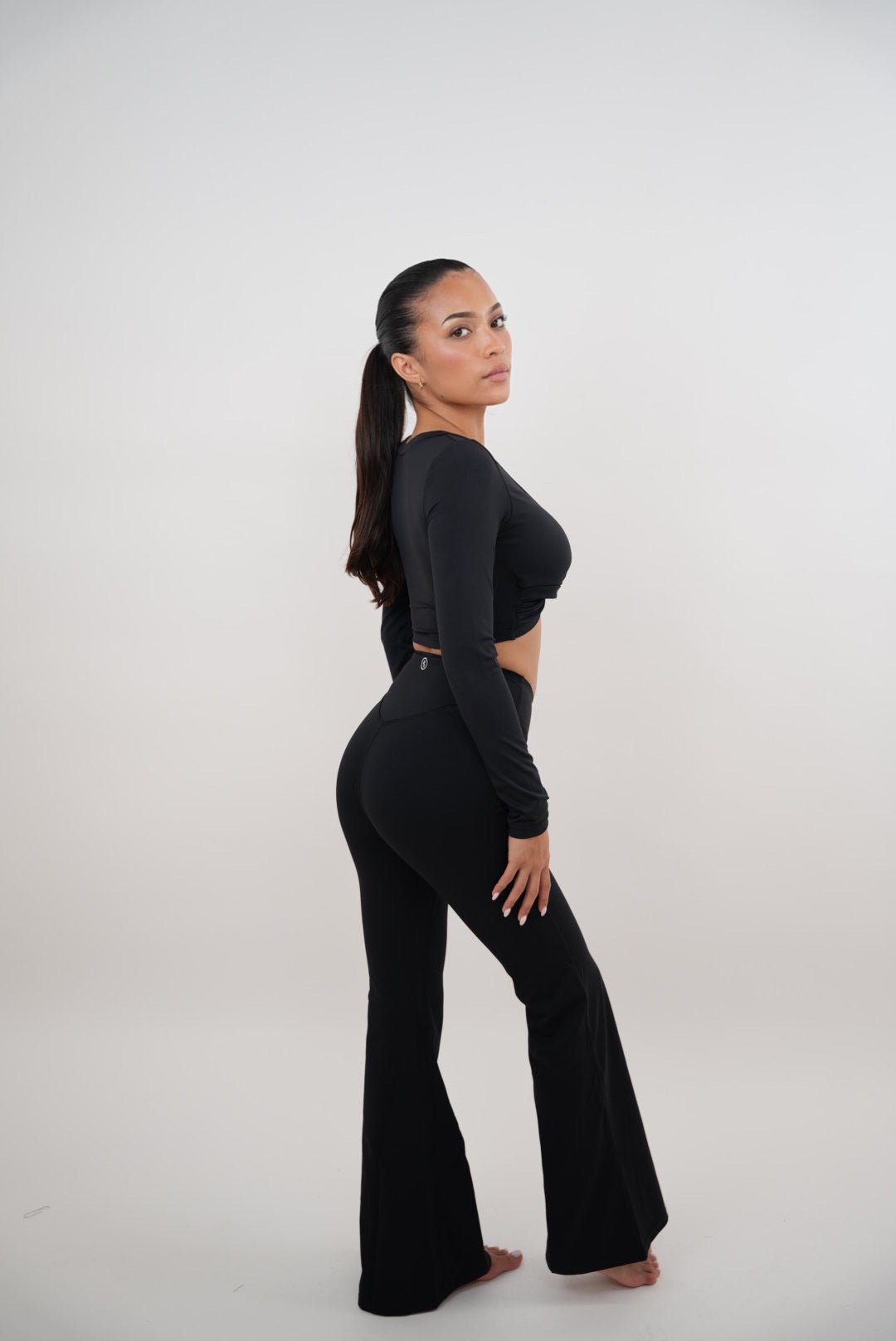 Black stretch flare legging by KIMITH BRAND, showing a close-up of the fitted waistband and flared leg design.