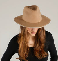 Packable wool coat from KIN THE LABEL Essentials Collection, shown in a neutral color, folded and ready for travel.