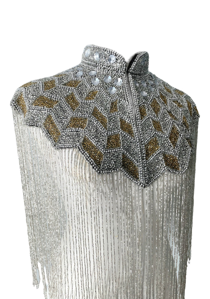 L'Jai Amor Gilded Halo Cape displayed on a mannequin with intricate gold detailing and flowing fabric.