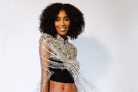 L'Jai Amor Gilded Halo Cape draped over a mannequin, showcasing its luxurious gold-toned design and elegant fabric details.
