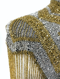 L'Jai Amor Golden Line Cape featuring a luxurious gold design and flowing fabric, displayed on a hanger against a neutral background.